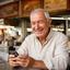 Longhuat Mulder, smiling senior man at a hawker centre using his phone